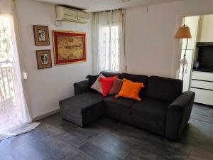 a living room with a black couch with colorful pillows at Apartament Melpomeny in Tarragona
