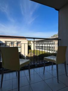 - un balcon avec deux chaises et une vue sur un bâtiment dans l'établissement Les appartements du Clos de la Chartreuse By Ateya, à Aix-en-Provence