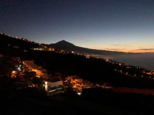 uma cidade à noite com uma montanha ao fundo em Apartamento Teide Piscina Climatizada em Sauzal