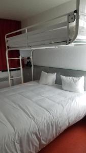 - un lit avec des draps et des oreillers blancs dans l'établissement Premiere Classe Brive La Gaillarde Ouest, à Brive-la-Gaillarde