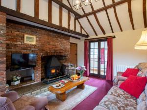 a living room with a brick fireplace and a table at 2 Bed in Geldeston HISN8 in Geldeston