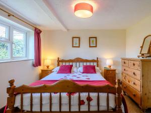 a bedroom with a wooden bed with red pillows at 2 Bed in Geldeston HISN8 in Geldeston