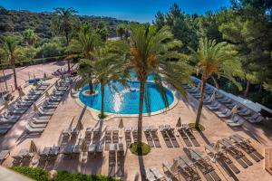 una vista aérea de una piscina con sillas y palmeras en Grupotel Club Cala Marsal, en Portocolom