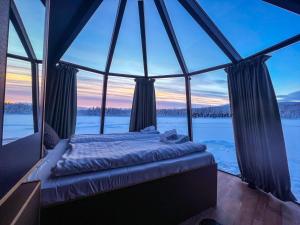 a bed in a room with a large window at Aurora Camp Kurravaara in Kurravaara