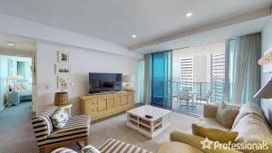 a living room with a couch and a television at Number 1 H Residences - WiFi, Parking & More by Gold Coast Holidays in Gold Coast