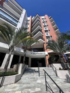 a large building with palm trees in front of it at Apartamento pé na areia em Riviera de São Lourenço in Riviera de São Lourenço