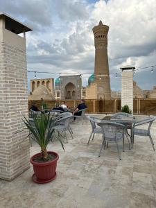 a patio with tables and chairs and a tower at GOLDEN MINARET by Terrace in Bukhara