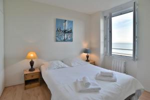 een slaapkamer met een wit bed en handdoeken bij Les Pieds dans le Sable - Appt vue mer in Saint-Cast-le-Guildo