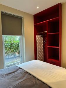 um quarto com uma cama com uma janela e um armário vermelho em Tiny House Bos em Moergestel