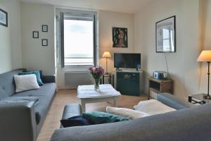 een woonkamer met 2 banken en een tv bij Les Pieds dans le Sable - Appt vue mer in Saint-Cast-le-Guildo
