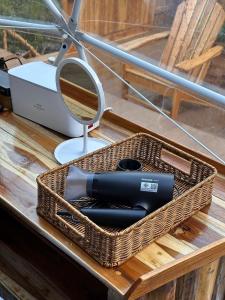 a basket with a hair dryer and a mirror on a table at Lhong Chiang Dao Glamping หลงเชียงดาว in Chiang Dao