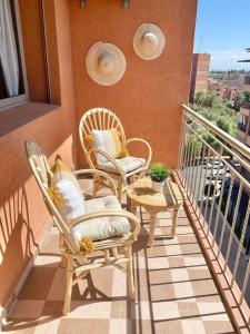 un balcón con 2 sillas y una mesa en el balcón en Bel appart wifi balcon et parking Marrakech centre en Marrakech