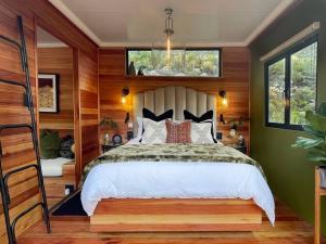 a bedroom with a bed in a room with wooden walls at Luxury Solace Cabin - River Cabin in Rawsonville