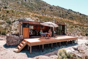 two people sitting under an umbrella in a tiny house at Luxury Solace Cabin - River Cabin in Rawsonville +27 photos