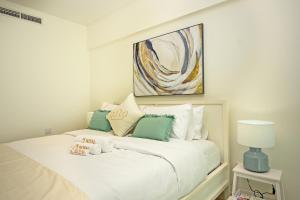 1BR Loft Soul Beach Escape - Mamsha Al Saadiyat في أبوظبي: غرفة نوم بسرير ابيض مع لوحة على الحائط