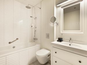 La salle de bains blanche est pourvue de toilettes, d'une baignoire et d'un lavabo. dans l'établissement Hotel Grimsborgir by Keahotels, à Ásborgir