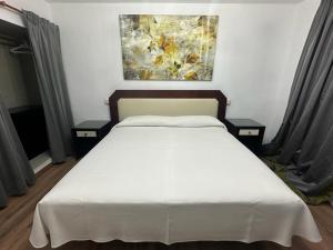 a bedroom with a white bed with two night stands at La Casona del Pinar Albergue in San Rafael