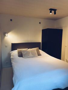 um quarto com uma grande cama branca com dois travesseiros em Studio Sarah em De Panne