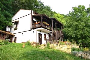 a white house with a balcony with flowers on it at Milkovata Guest House in Koshov +45 photos
