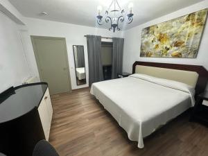 a bedroom with a large white bed and a chandelier at La Casona del Pinar Albergue in San Rafael