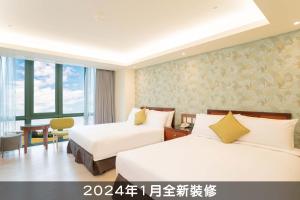a hotel room with two beds and a desk at Formosan Naruwan Hotel in Taitung City