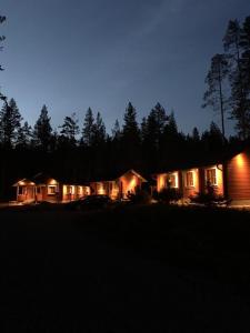 a house lit up at night with lights on at Lomanaamanka Naava-Cottage / Naava-hirsimökki in Syöte
