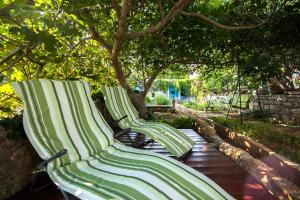 due panche verdi e bianche sedute sotto un albero di Holiday Home ART - Bol a Bol