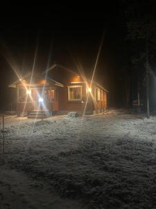 Lomanaamanka Naava-Cottage / Naava-hirsimökki في Syöte: كابينة في الثلج بالليل فيها انارات