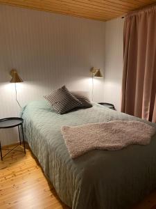 a bedroom with a bed with two lamps and a window at Lomanaamanka Naava-Cottage / Naava-hirsimökki in Syöte