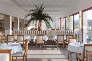 un ristorante con tavoli e sedie bianchi e una palma di Bonjur Hotel Thermal & Wellness Club a Ankara