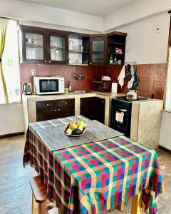 Una cocina con una mesa con un bol de fruta encima. en La Casa del Cerro, en Sucre
