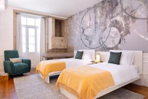 een slaapkamer met 2 bedden en een groene stoel bij Historical Penthouse at Cardosas Block in Porto
