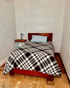 ein Bett mit einer schwarz-weißen karierten Decke in der Unterkunft La Casa del Cerro in Sucre