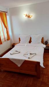 Una cama con sábanas blancas y toallas blancas. en Casa Schi en Straja