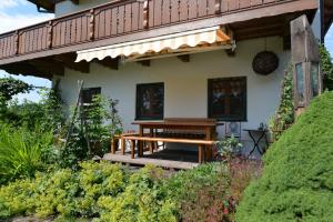 une maison avec un banc en bois devant elle dans l'établissement Ferienwohnung Kurz, à Rimsting