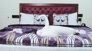 a white swan laying on top of a bed at Hotel Jakhu Heights in Shimla