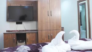two swans are sitting on a bed with a television at Hotel Jakhu Heights in Shimla