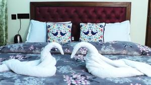 two swans made out of towels on a bed at Hotel Jakhu Heights in Shimla
