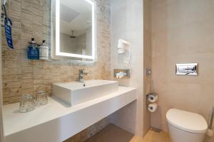 a bathroom with a sink and a toilet and a mirror at Maritim Antonine Hotel & Spa in Mellieħa