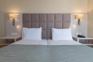 a bedroom with a large bed with two white pillows at Maritim Antonine Hotel & Spa in Mellieħa