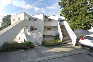 een wit gebouw met een trap op een parkeerplaats bij Apartman Liburna in Rijeka
