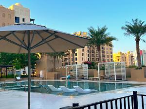 una grande piscina con sedie e ombrellone di Rahaal 2, Madinat Jumeirah Living, Umm Suqeim - Mint Stay a Dubai