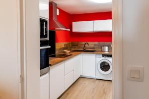 a kitchen with white cabinets and red walls at Les Létruns - Appart - 4 pers - Vue sur la mer in Saint Malo