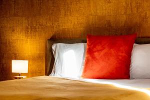 a bed with a red and white pillow and a lamp at Les Létruns - Appart - 4 pers - Vue sur la mer in Saint Malo