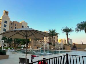 a patio with an umbrella and chairs and a pool at Rahaal 2, Madinat Jumeirah Living, Umm Suqeim - Mint Stay in Dubai