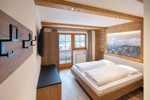 ein Schlafzimmer mit einem Bett und einem großen Fenster in der Unterkunft Tinahof in Wolkenstein in Gröden