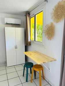 a kitchen with a wooden table and two stools at Bungalow Jazz - Bassin Manapany-Les-Bains in Saint-Joseph