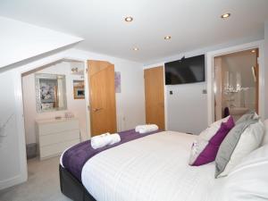 um quarto com uma grande cama branca com almofadas roxas em 1 Bed in Charlestown 53680 em Luxulyan