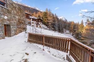 a building with a wooden fence in the snow at Appartement rénové avec sauna privé in Saas-Fee