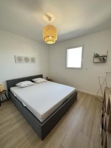 Un dormitorio con una cama y una lámpara de araña. en Bel appartement neuf vue mer, en LʼÎle-Rousse